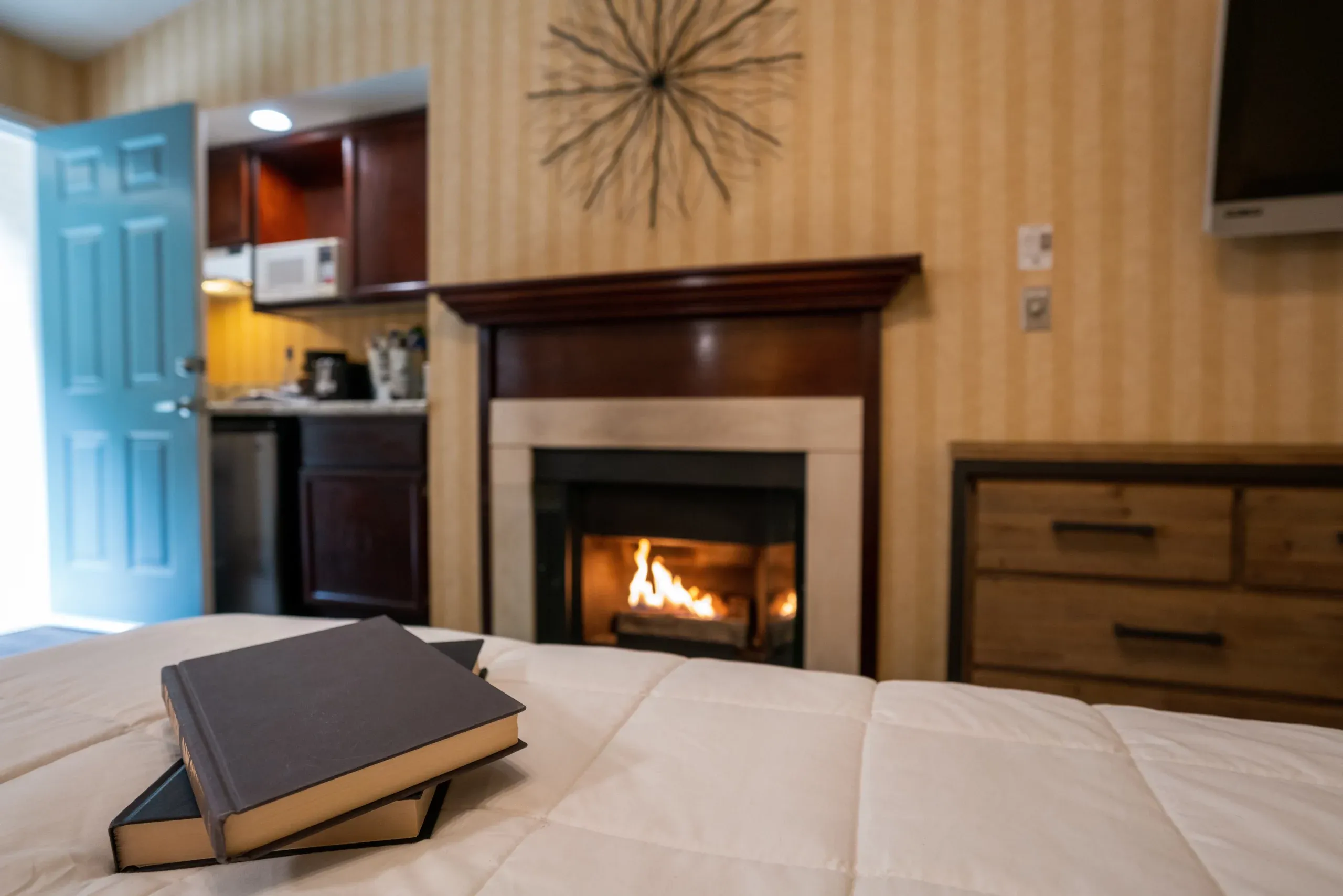 Stack of books on the bed with fireplace on in room at Yosemite view lodge